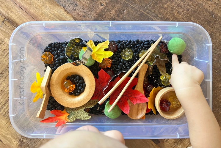 Toddler exploring a fall sensory bin learning through sensory play