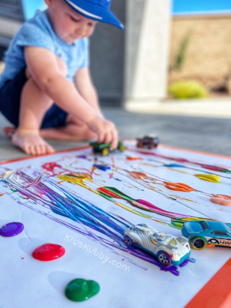 How to paint with toy cars! A fun art project for toddlers, preschoolers and older kids! My 2 year old and 12 year old boys had so much fun with this outdoor activity. So simple to do with cheap supplies!