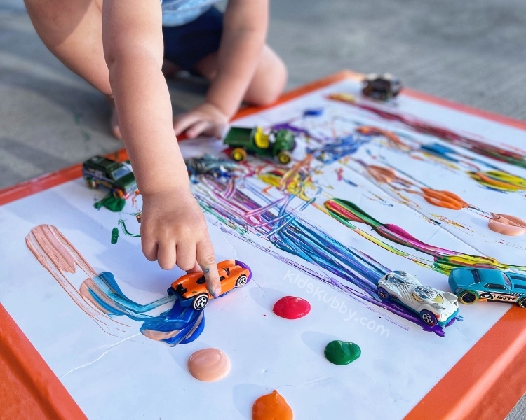 Your kids are going to love painting with cars. It is so easy with very little supplies you most likely already have at home-washable paint, toy cars, and paper. Let your child create their own little art piece by driving the cars through the paint.