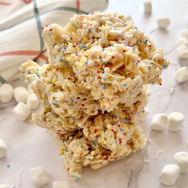 Are you looking for a fun birthday snack for kids? Cake Batter Rice Krispie Treats with rainbow sprinkles are gooey and delicious and kids just gobble them up. Make this easy no bake treat with just a few simple ingredients including crispy rice cereal, butter, marshmallows, dry cake mix, and rainbow sprinkles for a dash of fun! You can take these delectable morsels up a notch by adding a bit of marshmallow creme. Cake batter rice krisipes are fun, yummy, and easy to make in less than 10 minutes.