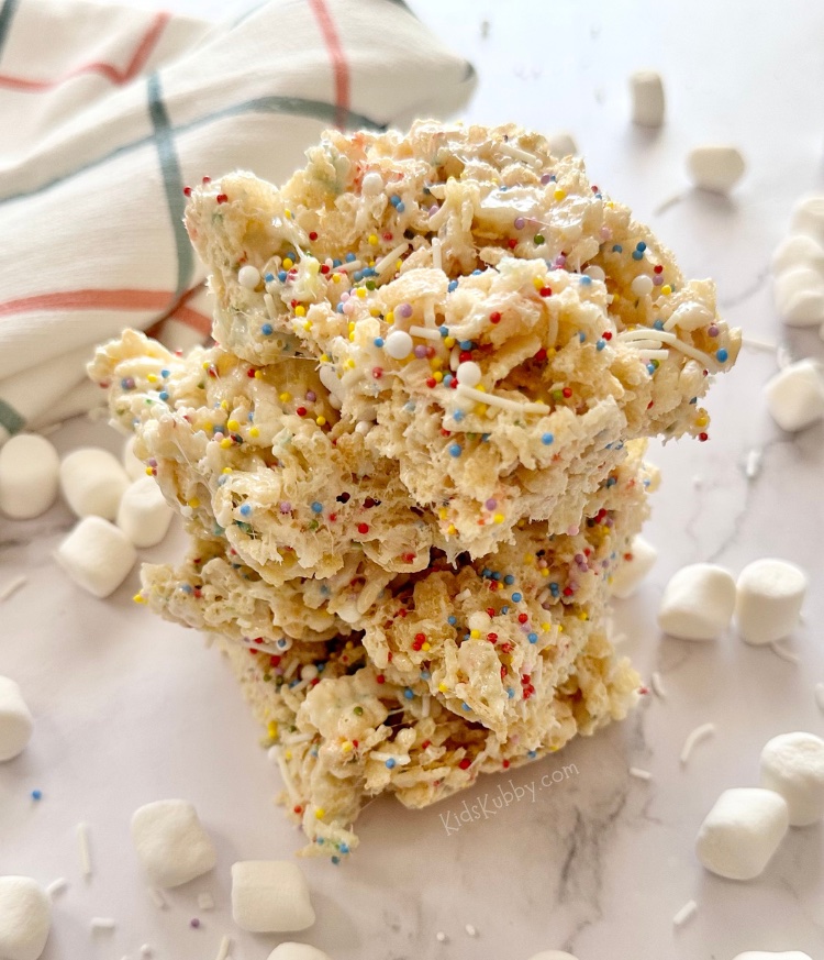 Are you looking for a fun birthday snack for kids? Cake Batter Rice Krispie Treats with rainbow sprinkles are gooey and delicious and kids just gobble them up. Make this easy no bake treat with just a few simple ingredients including crispy rice cereal, butter, marshmallows, dry cake mix, and rainbow sprinkles for a dash of fun! You can take these delectable morsels up a notch by adding a bit of marshmallow creme. Cake batter rice krisipes are fun, yummy, and easy to make in less than 10 minutes.