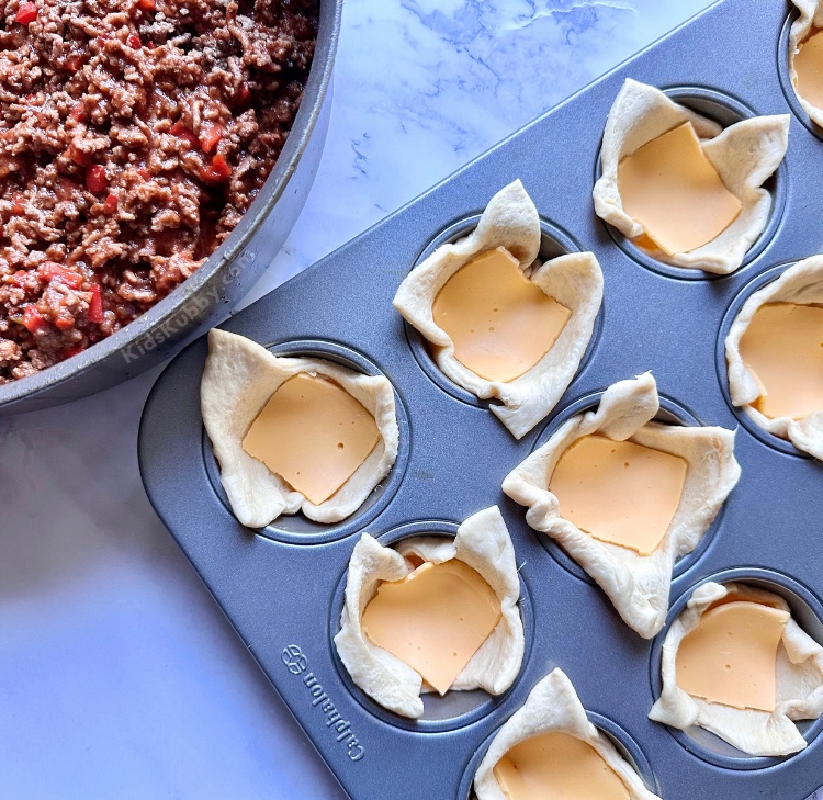 Pillsbury crescent roll dough stuffed full of a delicious mixture of ground beef, melted cheese, bell peppers, and sloppy joe sauce combined in a muffin pan to create handheld sloppy joe cups. So yummy and kid approved! This is one of my favorite family dinner recipes for busy school nights because these sloppy joe cups are so easy to make with just a few basic ingredients in a muffin pan.