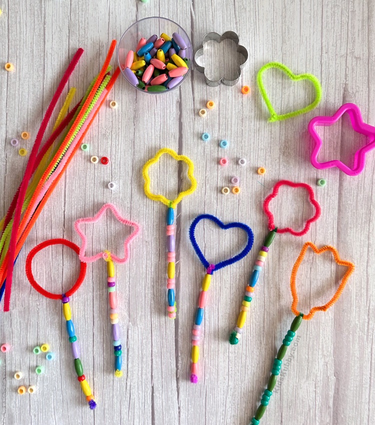 Simple outdoor craft idea for kids using pipe cleaners, beads, and cookie cutters. Kids will love making their very own magical DIY bubble wands. These bubble wands make a great party activity for kids. Try making bubble wands at your next birthday party or family gathering to keep kids entertained outdoors! Don't forget a lot of bubble solution because your kids are going to be blowing bubble for hours with this simple to make bubble wand craft.