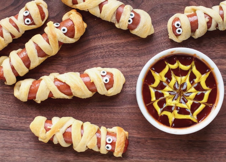 Are you having a Halloween party this year? You MUST add these mummy dogs to your menu. Take a juicy hot dog, wrap it in strips of crescent roll dough and bake for 15 minutes. Add a couple of candy eyes and you have the perfect Halloween treat that everyone will love. This simple recipe is a great family dinner idea to have before trick or treating. My kids love to take these for lunch with a side of spider web ketchup. Give this halloween recipe a try today.  