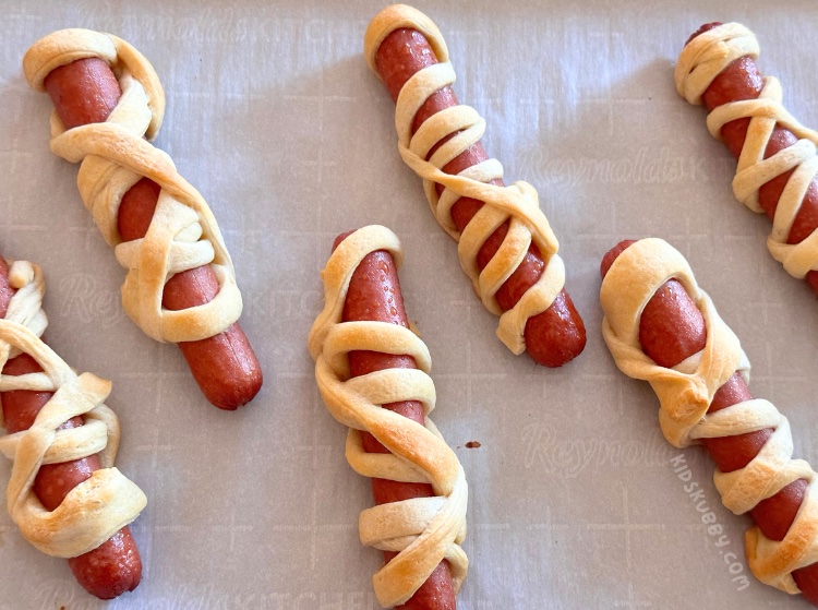 Flaky, butter crescent rolls wrapped around juicy hot dogs. Add some candy eyes and you have the perfect recipe for Halloween mummy dogs. This fun halloween treat is so easy to make and kids absolutely love them! Mummy dogs are great fro your next halloween party or spooky get together. Try making these ahead of time and rewarming in the air fryer for 5 minutes. Such  a great after school snack idea for October. 