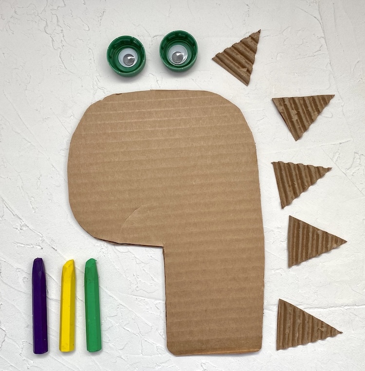 How to make a cute dinosaur craft with cardboard and plastic bottle caps! An easy and fun craft for preschoolers to make at home or school. 