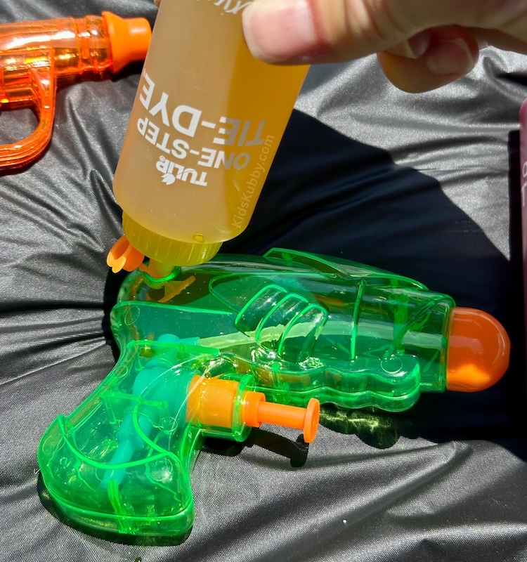Make vibrant tie dye shirts with kids using water guns! This DIY craft is simple, messy, and so much fun for summer. Check out this budget friendly art project today.