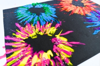 Colorful and glittery paper fireworks made with empty toilet paper rolls and paint.