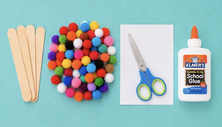Large popsicle sticks, craft pompoms, cardstock, glue, and scissors for making craft popsicles.