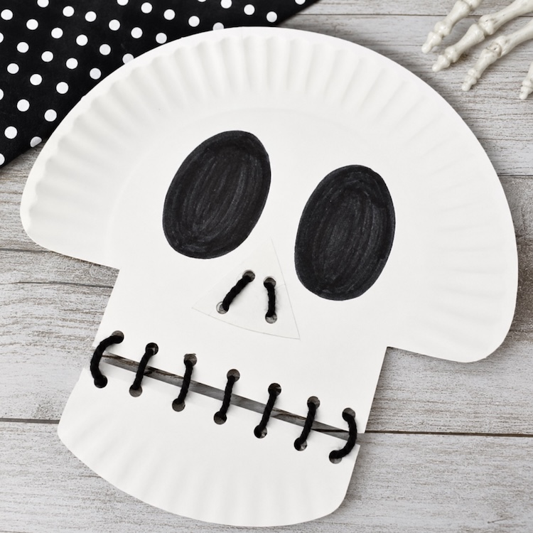 DIY Skeleton craft for kids to make on Halloween using a white paper plate and black yarn. 