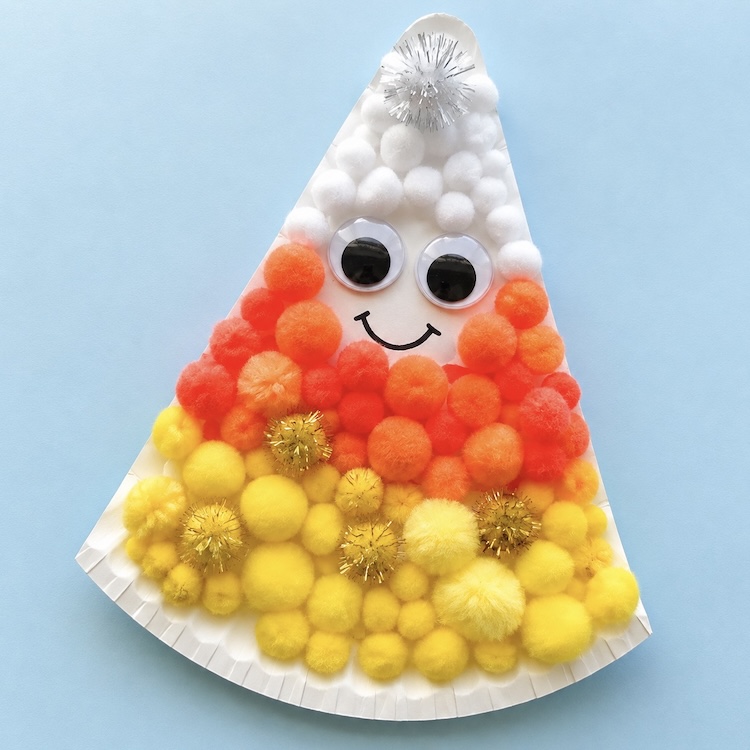 How to make a paper candy corn craft with orange, yellow, and white craft pom poms. 