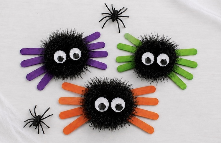Creepy spider craft for Halloween made with colorful popsicle sticks, black pom poms, and googly eyes.