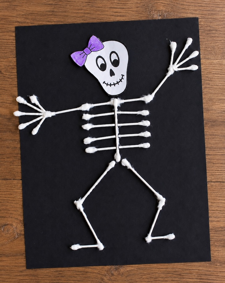 Simple, low mess Halloween craft for preschool age kids to make at home. How to make paper skeletons with cotton swabs! A fun and easy art project that's cheap to make with common supplies you already have.