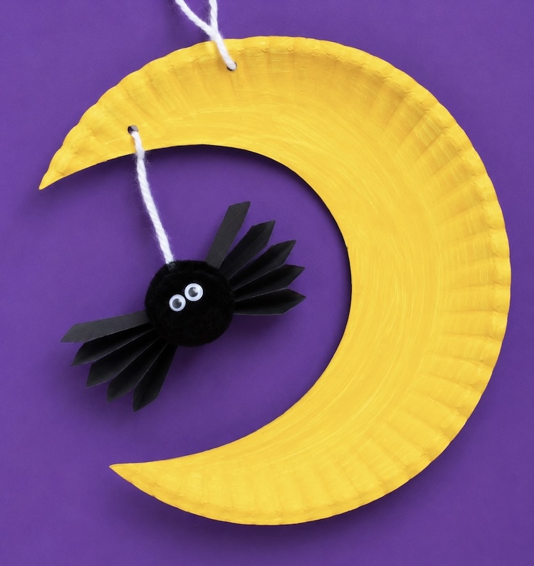 Crescent moon paper plate craft with a dangling spider for Halloween. An easy craft idea for kids to make. 