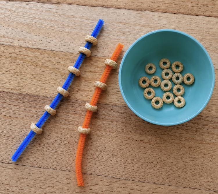 Cheerios cereal threaded onto fuzzy craft pipe cleaners for an easy fine motor activity for toddlers and babies.
