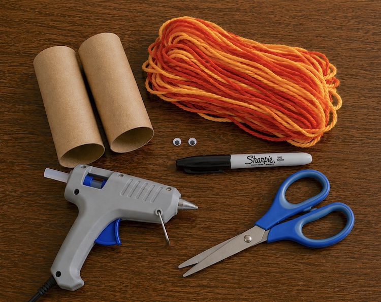 Supplies needed to make this easy lion craft for kids: recycled toilet paper roll tubes, orange yarn, glue, black marker, scissors, and googly eyes. 
