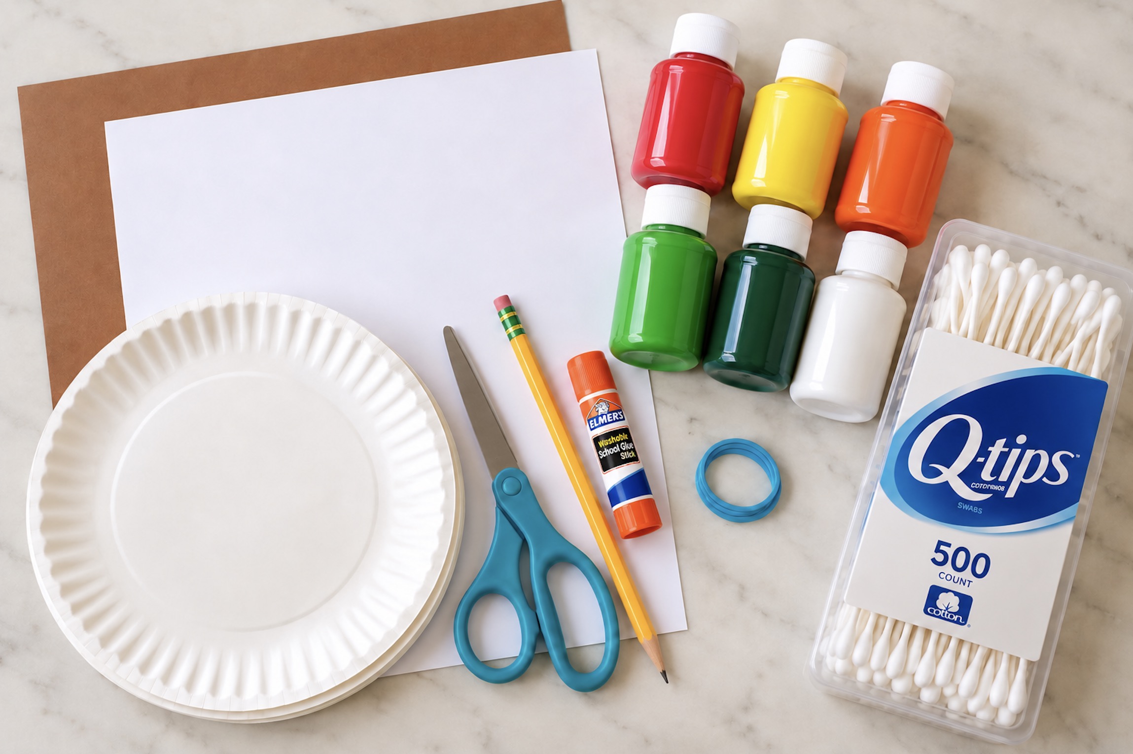 Construction paper, paper plates, scissors, paint, and q-tips on a counter ready for making an easy art project for kids.