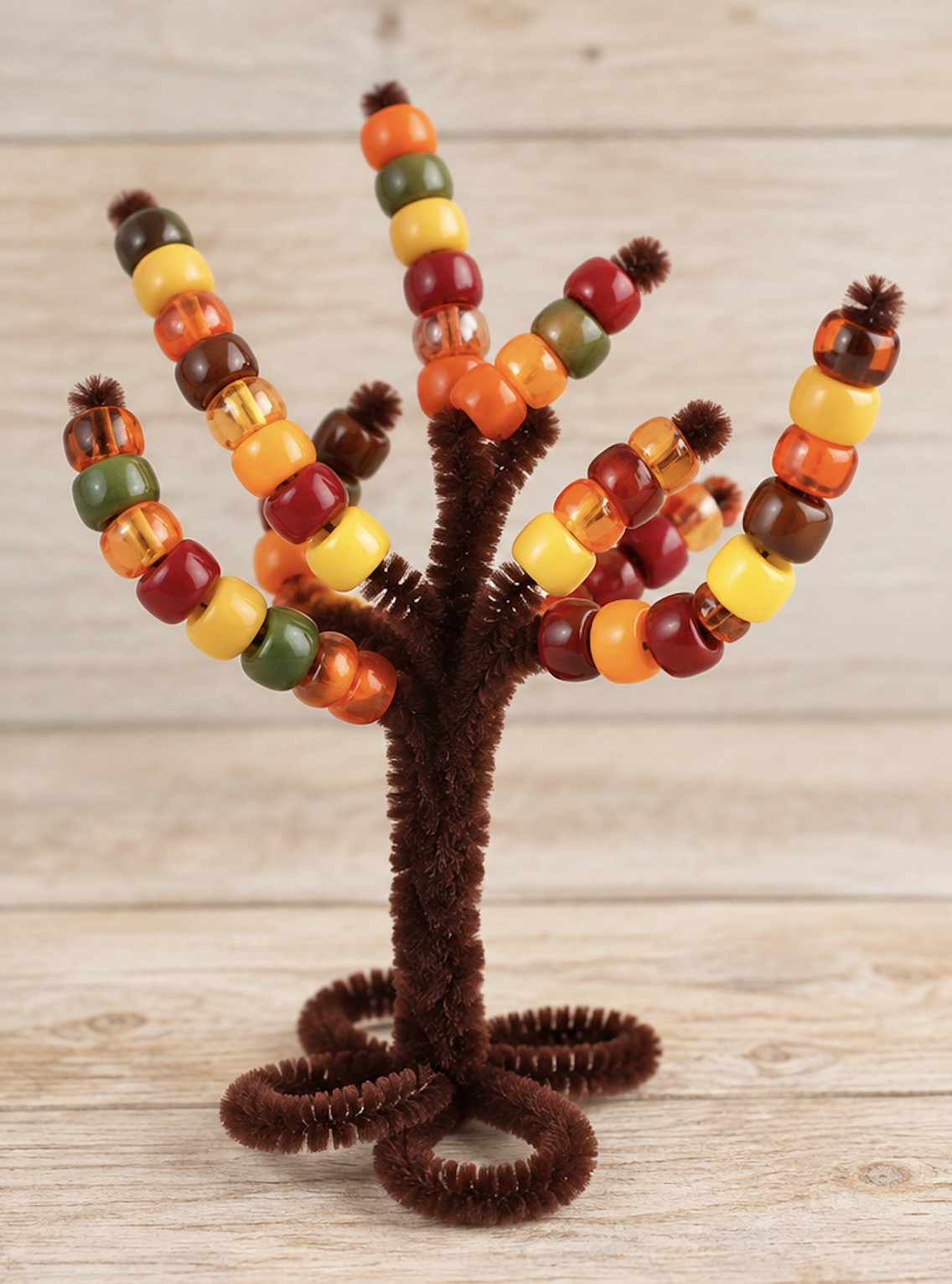 How to make an easy pipe cleaner tree trunk for lacing pony beads onto. A fun learning activity, craft, and fine motor skill practice for young children to practice hand eye coordination and color recognition.