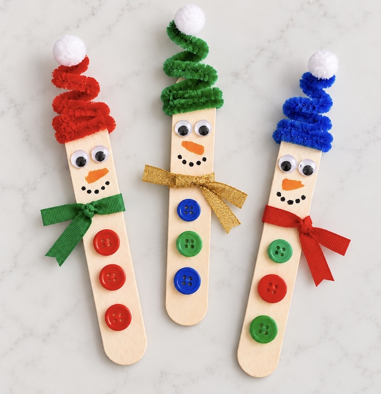 Cute snowmen for Christmas made with popsicle sticks with adorable pipe cleaner hats. A DIY craft for kids to make and use for decorations during the holidays.