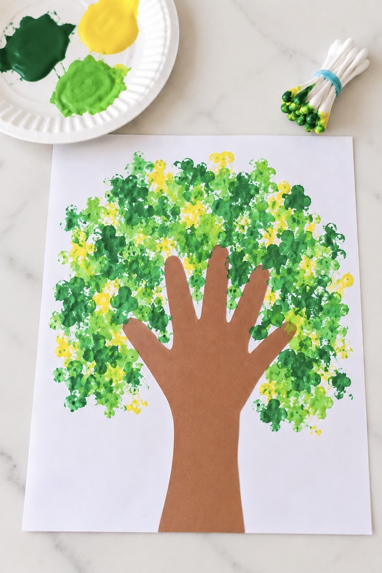 DIY Tree art craft for kids, preschool age and older. This easy art is made with a handprint cut-out tree trunk, then kids can paint on leaves with q-tip bundles by dabbing them in paint and then all over the paper.