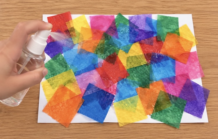 Spraying tissue paper on white cardstock to make magical color transfer art.