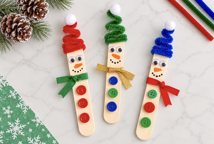 If you're looking for easy Christmas craft ideas for kids, break out your craft sticks for this simple holiday project! These adorable popsicle stick snowmen are fun to make with pipe cleaners and buttons. Hang them on your tree or use them to decorate your house!