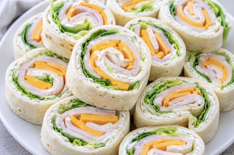 How to make a cold quick lunch for kids. Easy tortilla rollups made with deli turkey meat, cheddar cheese, lettuce, and seasoned cream cheese.