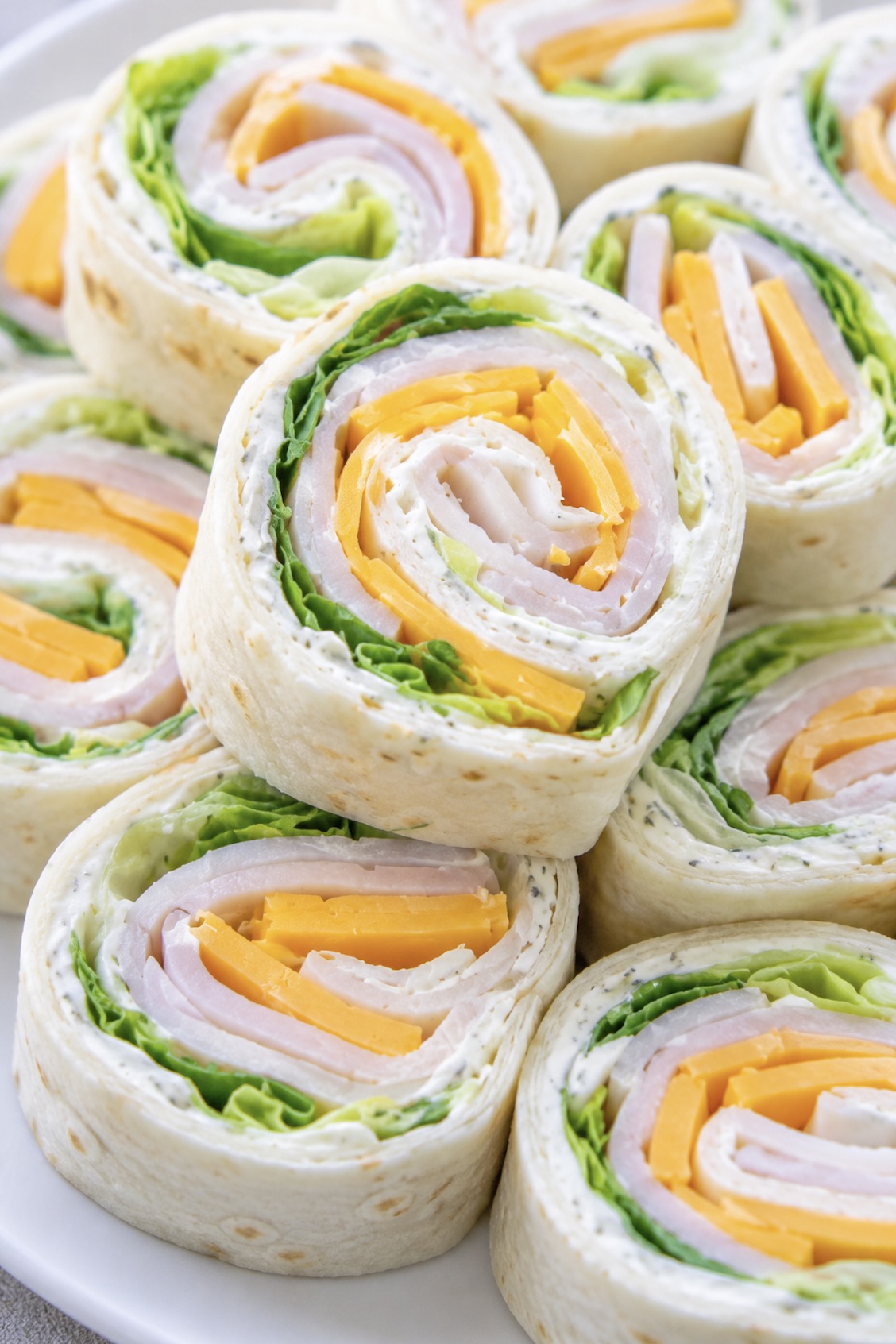 Close up view of turkey and cheese tortilla pinwheels on a plate ready to eat for a cold and yummy lunch.
