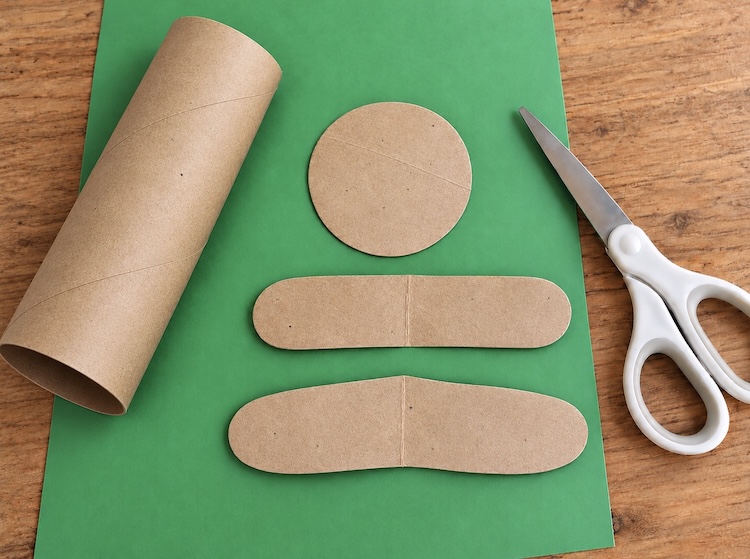 Step two of making cute gingerbread men out of toilet paper rolls, cutting the shapes out for the arms, legs, and head.