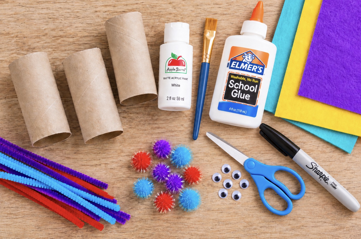 Craft supplies needed for this snowman craft include toilet paper rolls, felt, pom poms, pipe cleaners, googly eyes, white paint, scissors, glue, and a black pen.