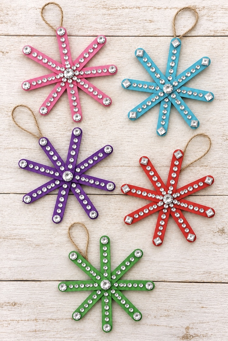 How to make easy snowflake Christmas ornaments for your tree with popsicle sticks and rhinestone stickers. An easy holiday craft for kids that's low mess and fun to make!