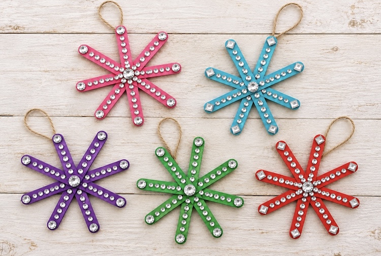 How to make easy snowflake ornaments with colorful popsicle sticks and rhinestone stickers. An easy Christmas craft for kids that's low mess and includes simple supplies.