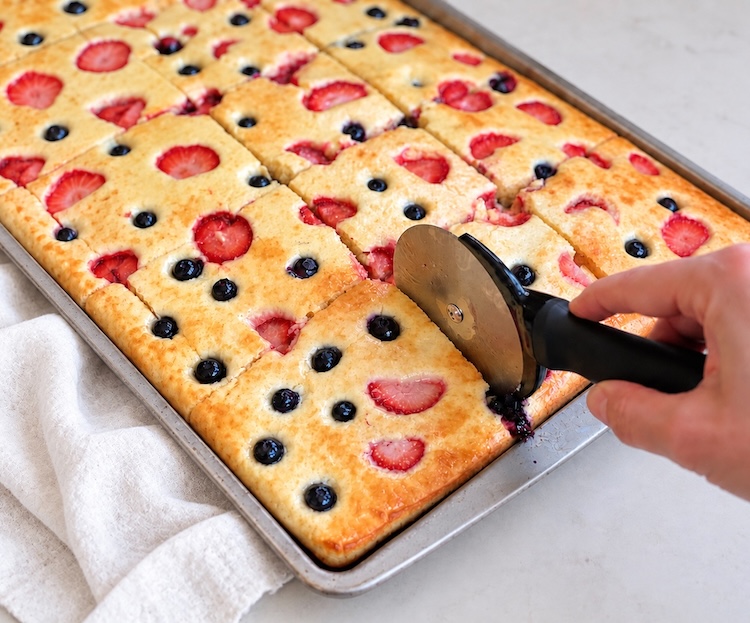 How to make sheet pan pancakes. Bake pancake mix batter in the oven on a greased sheet pan, brush with melted butter, then cut into small portions with a pizza cutter for an easy kid-friendly breakfast that's fast to make.