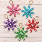 Popsicle stick snowflake ornaments are an easy, low mess Christmas craft for kids to make at home. Decorate them with rhinestone stickers and hang them on your Christmas tree for the holidays. So simple but really pretty!