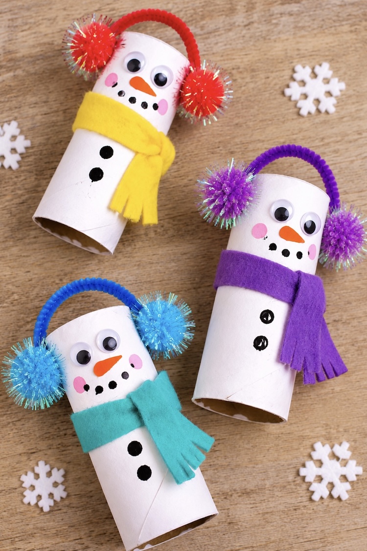DIY Christmas Craft Tutorial. Learn how to make the most adorable DIY snowmen with recycled toilet paper rolls, white paint, felt scarves, and earmuffs made out of pipe cleaners and fuzzy pom-poms.