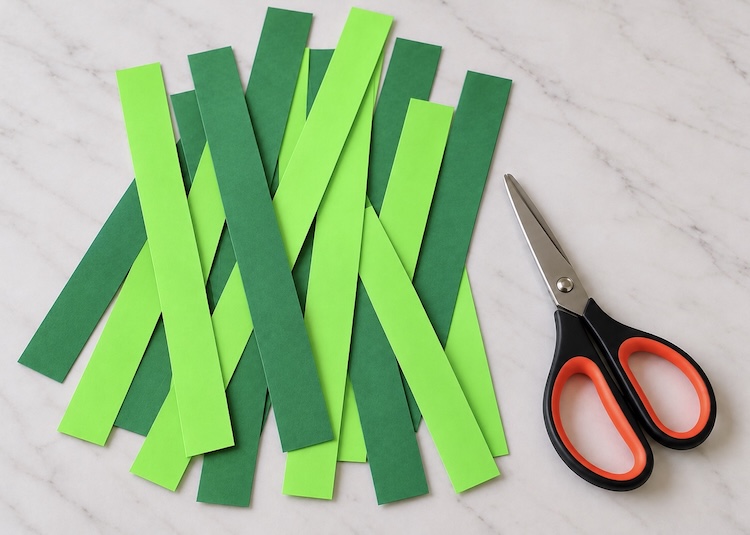 Cutting a variety of green colored construction paper into long strips to make a DIY wreath.