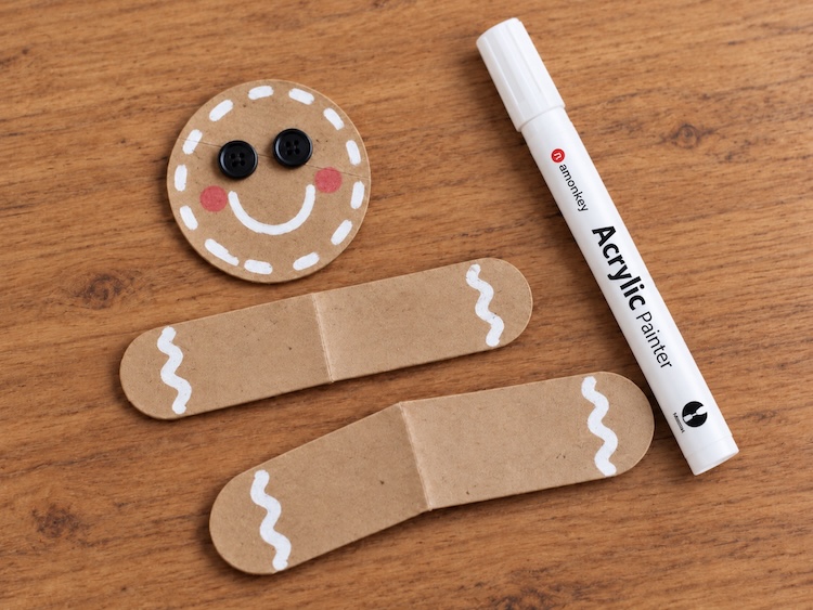 Step three decorating the face, arms, and legs with a white acrylic pen and cute button eyes.