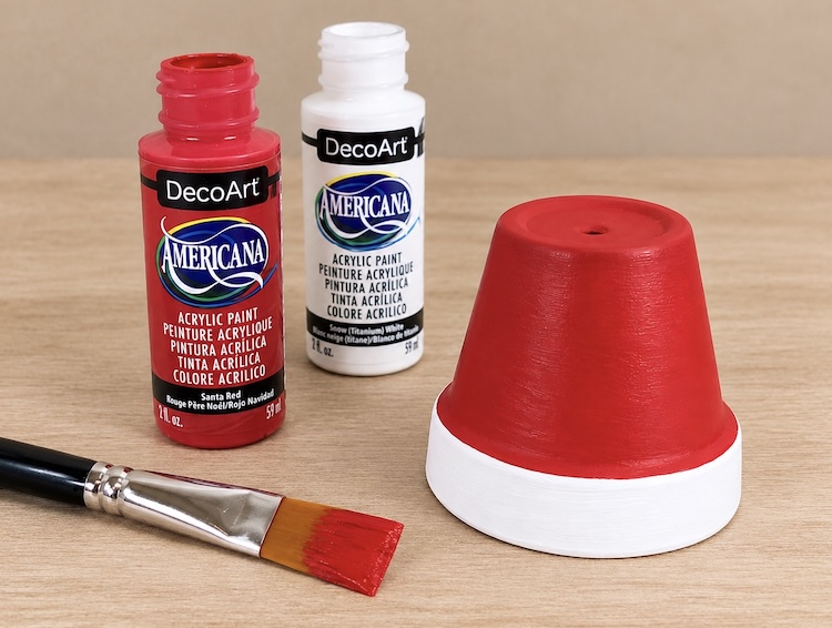 Mini clay pot painted red and white to look like a Santa hat. 