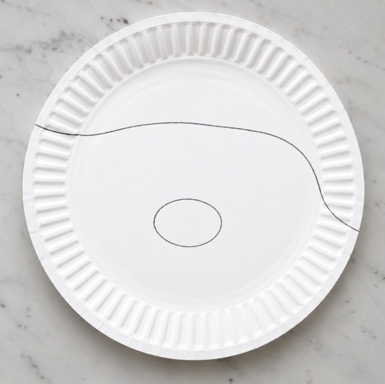 Step one of making a paper plate santa craft. Draw an outline of the hat and nose that its easy for preschoolers to paint with a guide. 
