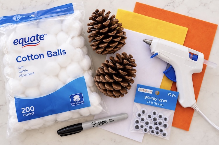 Craft supply list for making snowy owls including pinecones, cotton balls, hot glue, felt, a Sharpie pen, and googly eyes. 
