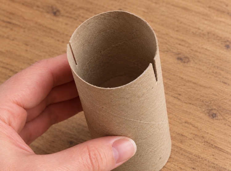 Step one of making toilet paper roll gingerbread men. Cut slits in the toilet paper roll tube body for the arms and legs to slide into later.